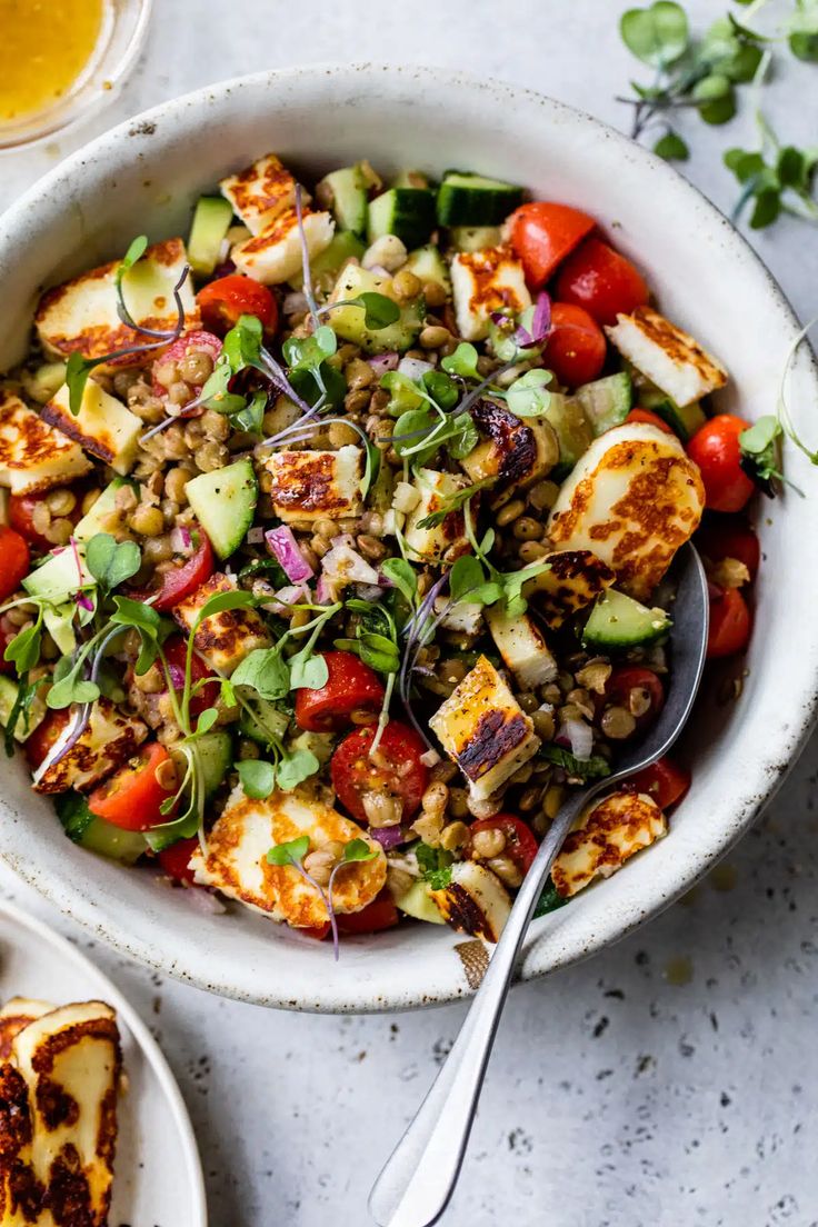 a white bowl filled with salad next to two slices of bread on top of a table