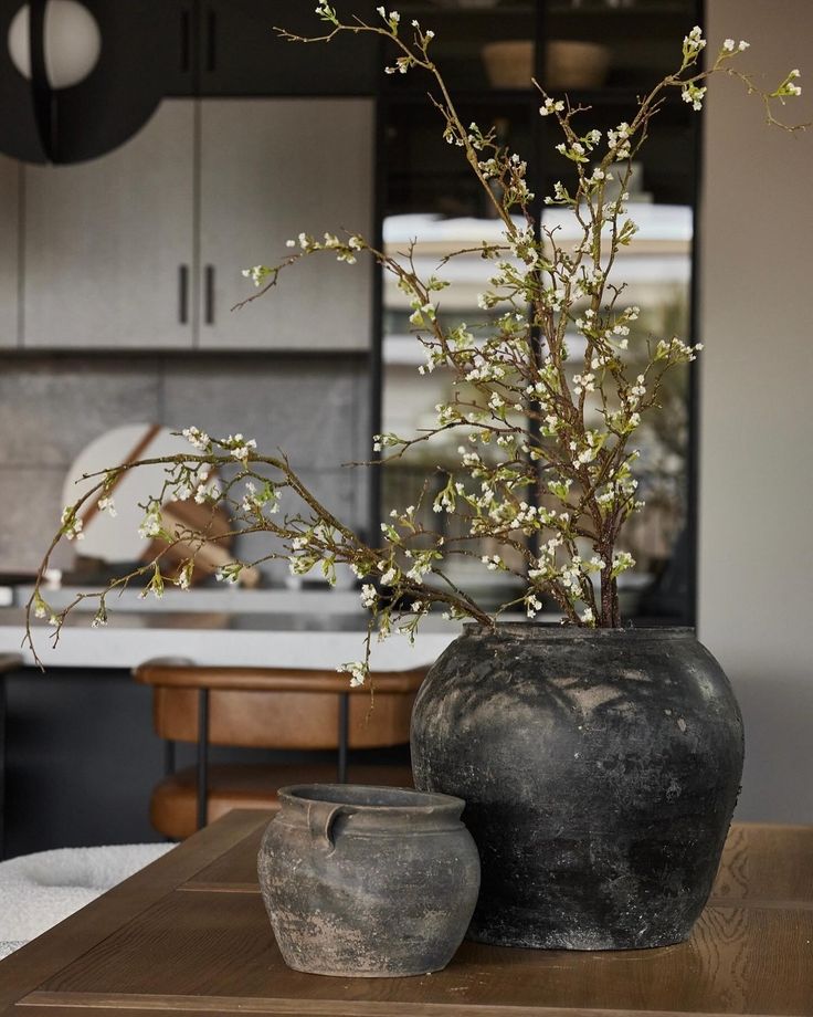 a vase with some flowers in it sitting on a table next to a potted plant