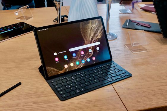 an open laptop computer sitting on top of a wooden table next to a tablet pc