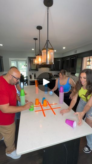 a group of people standing around a kitchen table with cups on it and one person holding a bottle