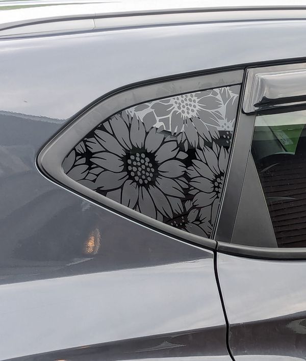 the side window of a car with flowers painted on it's side door and sunroof