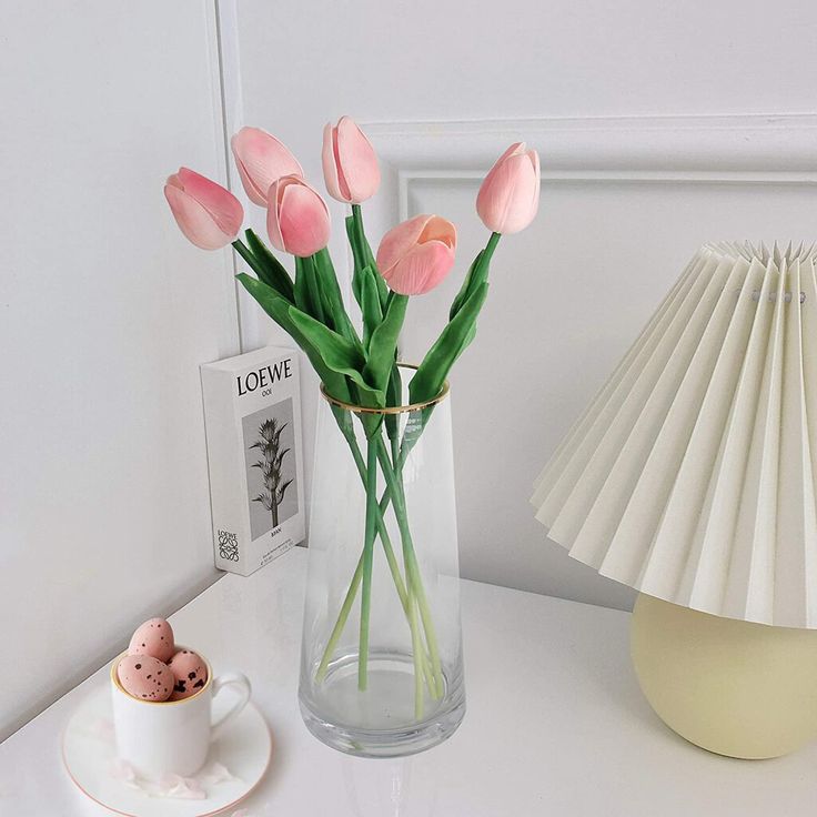 purple tulips in a vase next to a white lamp