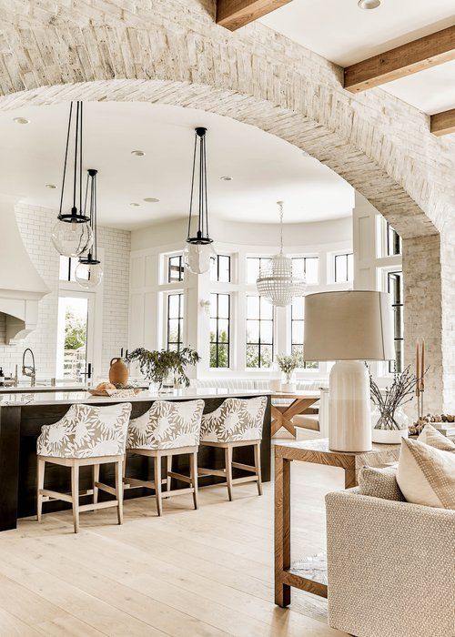 a kitchen and living room with an archway leading to the dining area is pictured in this image