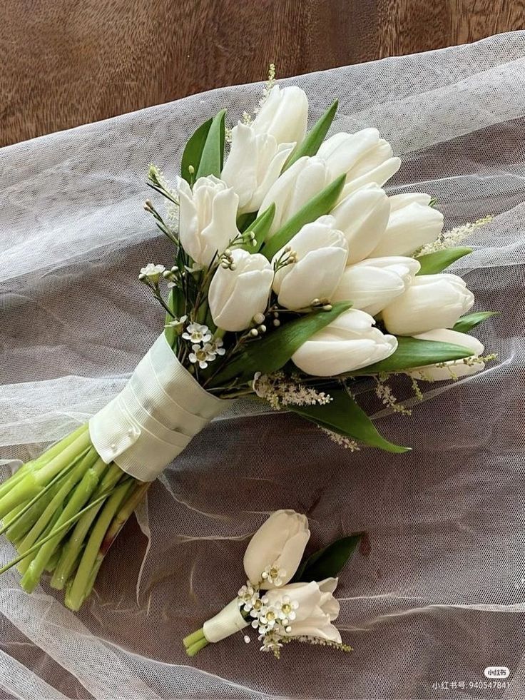 a bouquet of white tulips and other flowers on a tableclothed surface