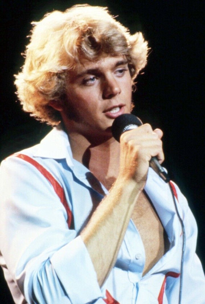 a man with blonde hair holding a microphone