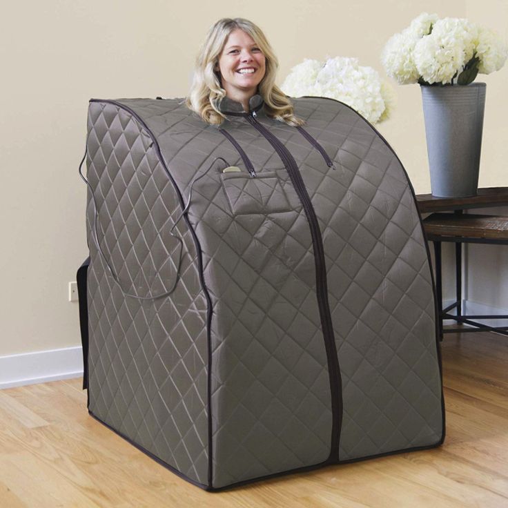 a woman sitting on top of a chair covered in a quilted blanket and smiling at the camera