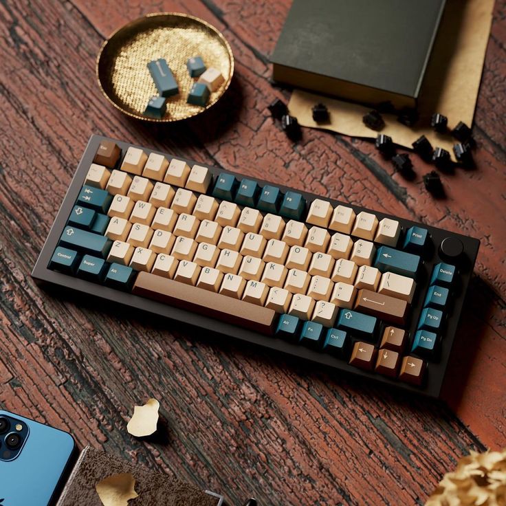 a computer keyboard sitting on top of a wooden table next to a phone and other items