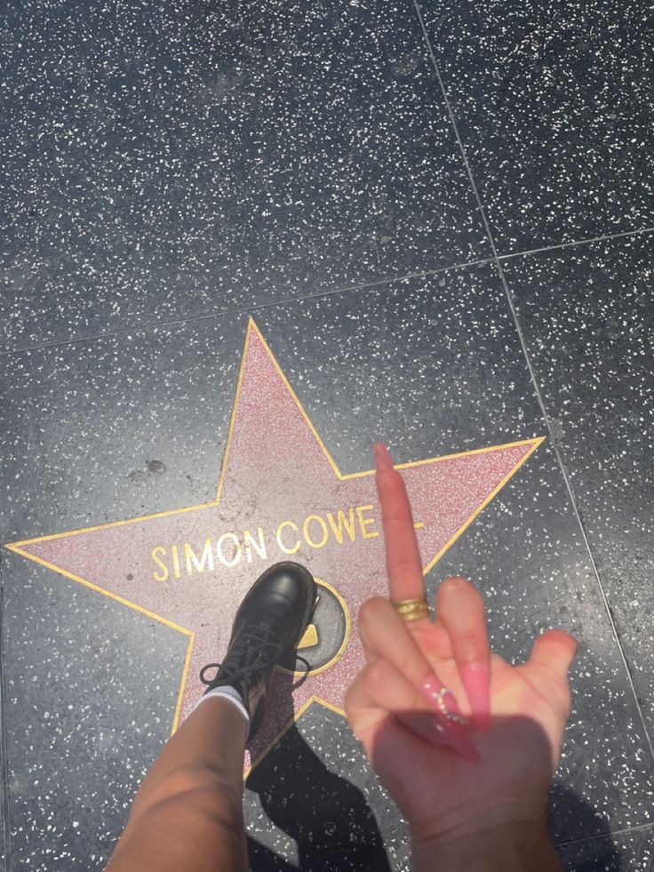 someone pointing at the star on the hollywood walk of fame with their fingers in the air