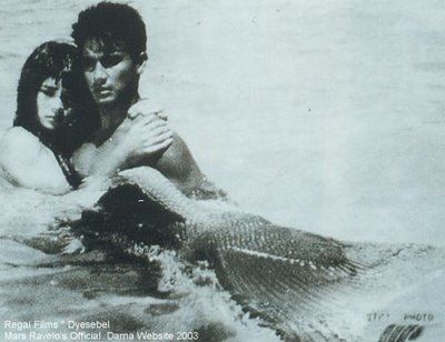 a man and woman are in the water with a mermaid tail on their back while holding each other