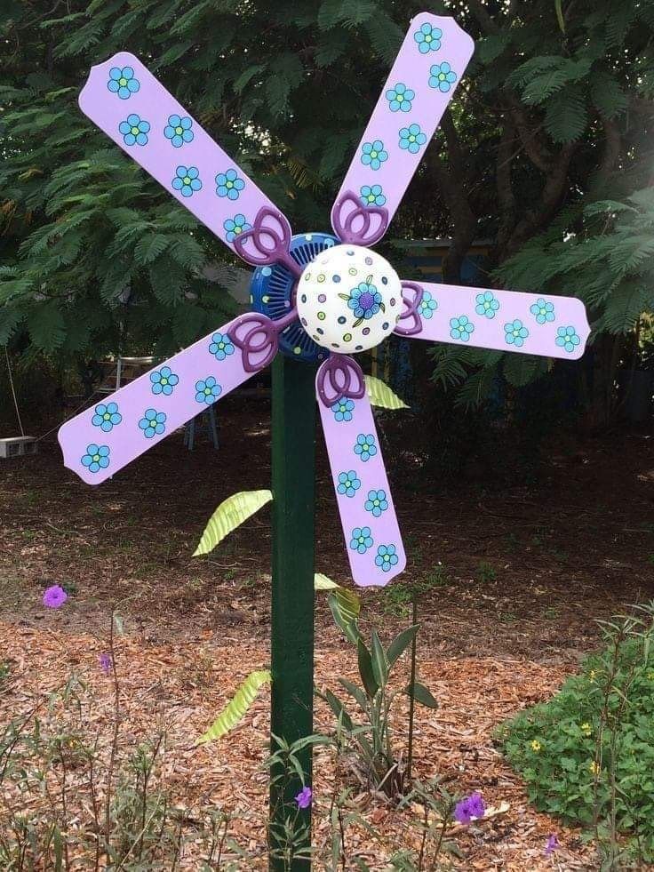 a purple and blue pinwheel with flowers on it sitting in the middle of some grass