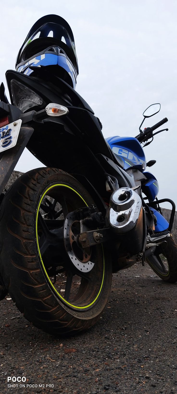 a blue and black motorcycle parked on top of a dirt road next to another bike