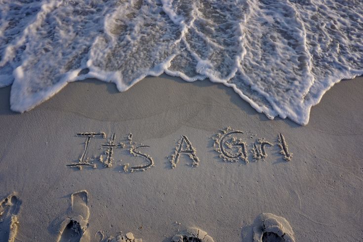 it's a girl written in the sand at the beach