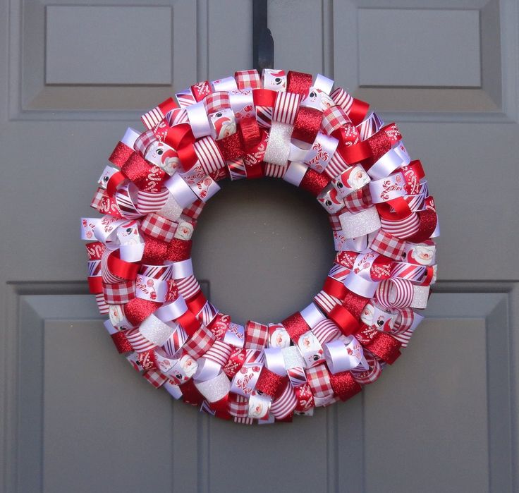 a red and white christmas wreath hanging on the front door