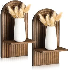 two white vases with brown feathers in them on wooden shelves against a white background