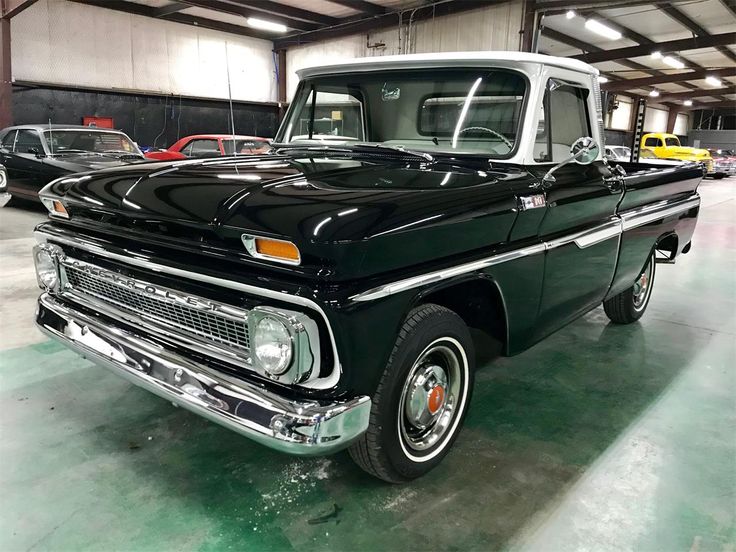 an old black pickup truck parked in a garage