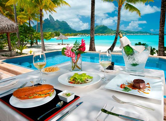 an outdoor dining table with food and drinks by the pool at a tropical resort in borabuda island, borabuda