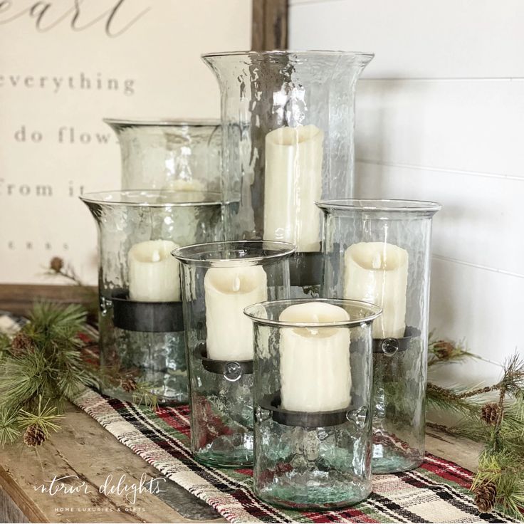 a table topped with lots of glass vases filled with candles