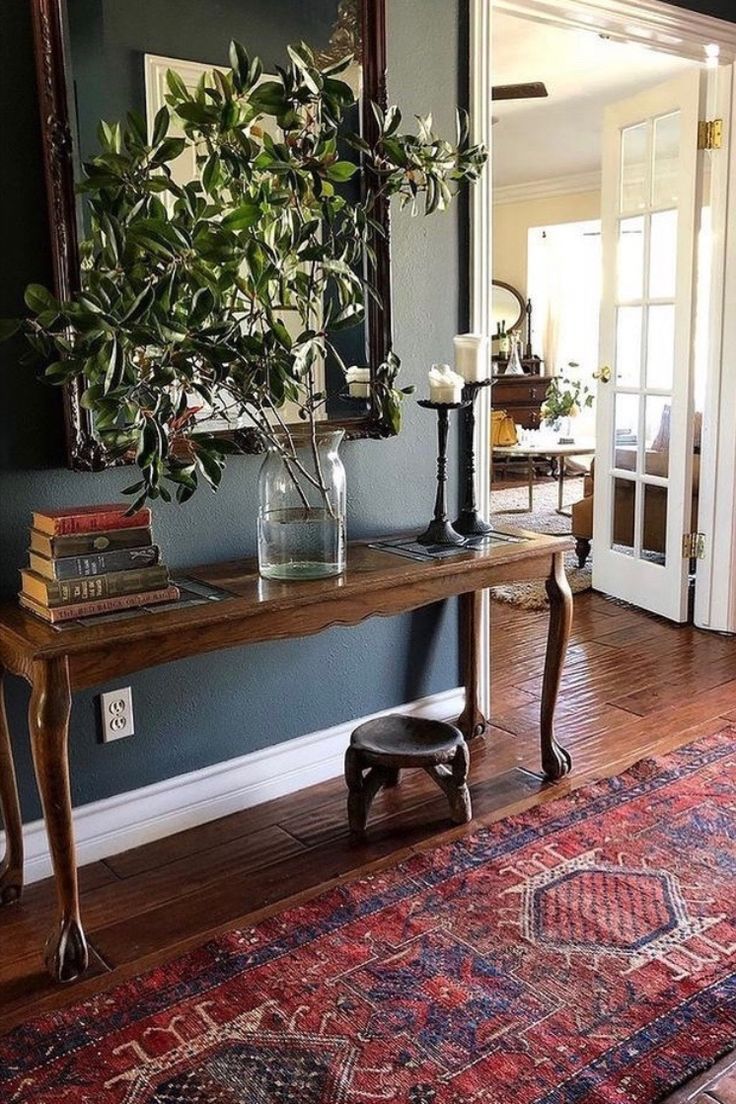 a room with a table, mirror and rug on the floor in front of it