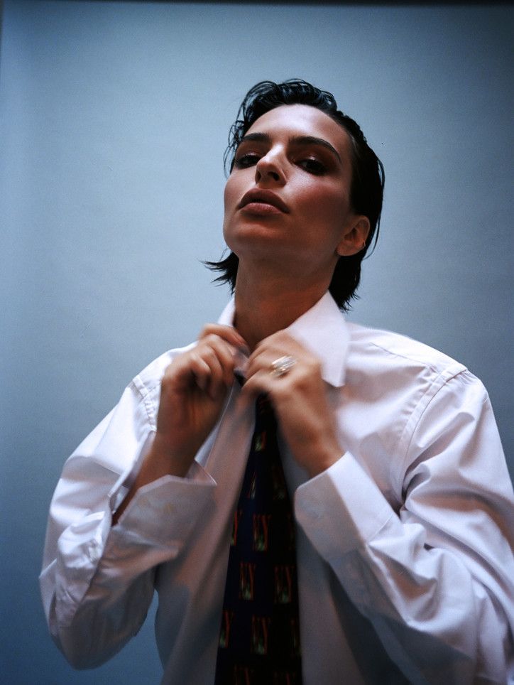 a man adjusting his tie in front of a blue background with the caption's name