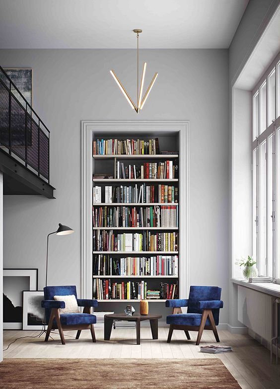 a living room with two chairs and a book shelf full of books in the corner