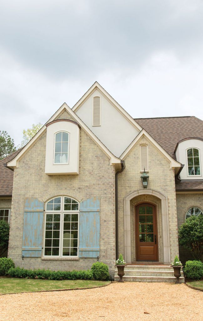 a large brick house with blue shutters on the front door and windows in it