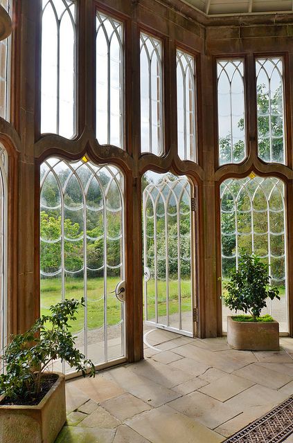 the inside of a building with large windows and potted plants in front of them