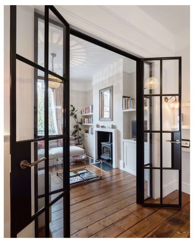 an open door leading to a living room with wood flooring and furniture in it