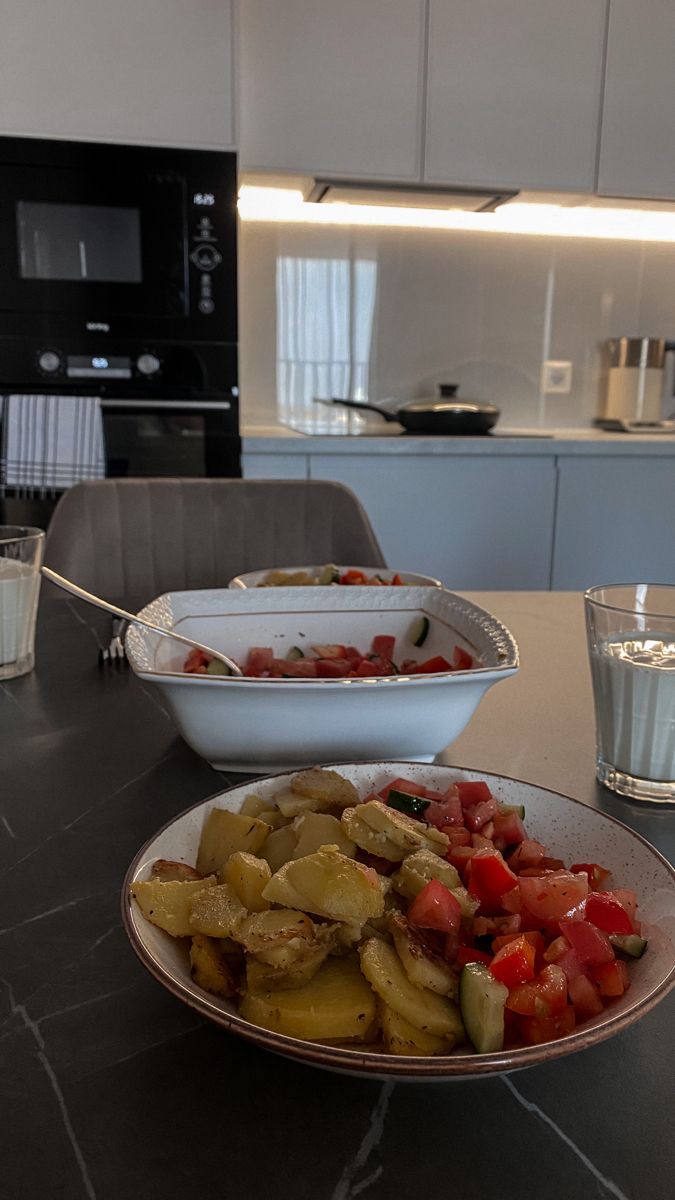 a table with plates of food on it next to a glass of water and an oven in the background