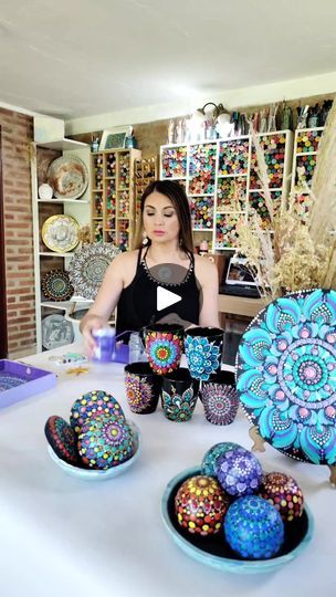 a woman is standing in front of some decorated eggs on a table with other items