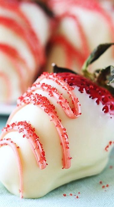 a close up of a piece of cake with white frosting and red sprinkles