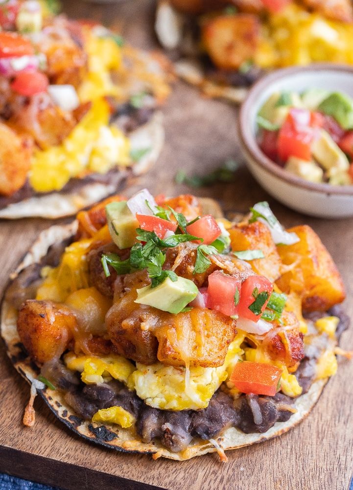 mexican food is served on tortillas with salsa and avocado in the background