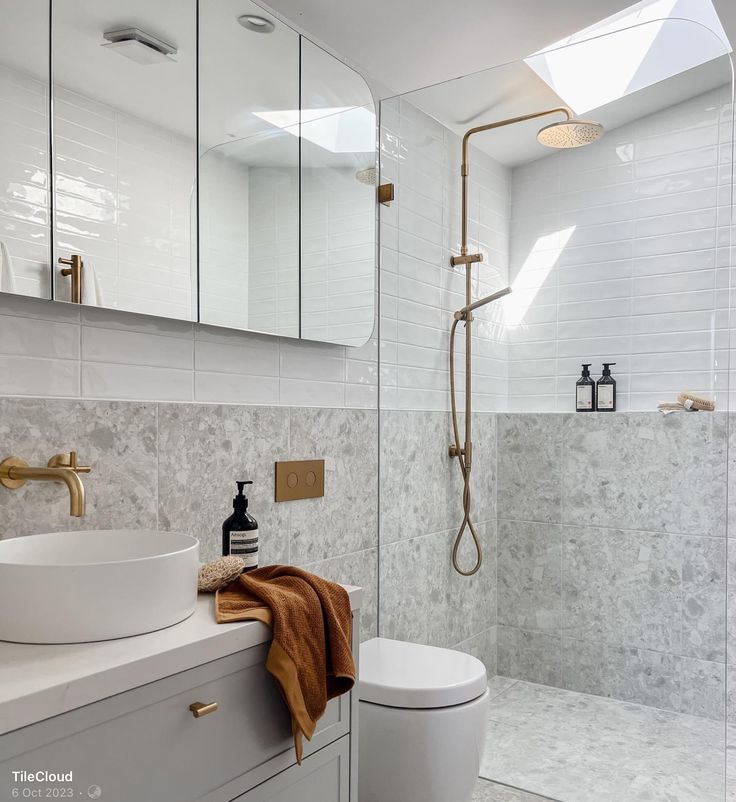 a bathroom with a sink, toilet and shower head mounted to the side of the wall