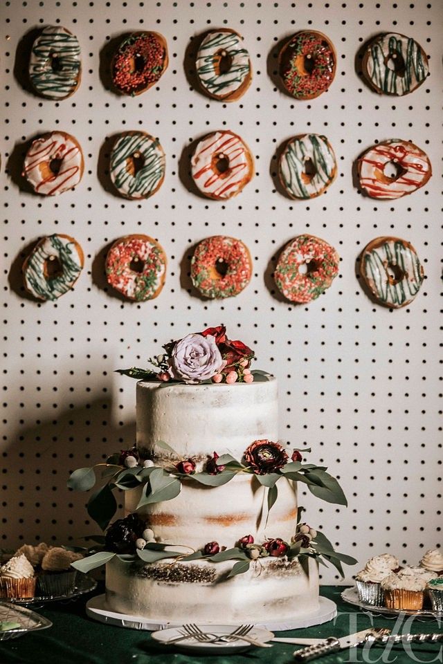 a wedding cake with donuts on the wall behind it