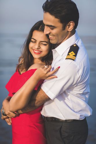 a man and woman hugging each other in front of the ocean