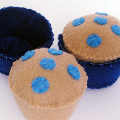 three small blue and brown cupcakes on a white surface with holes in the middle