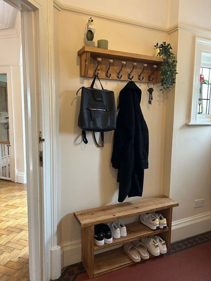 a coat rack with shoes hanging on it next to a wooden bench in a hallway