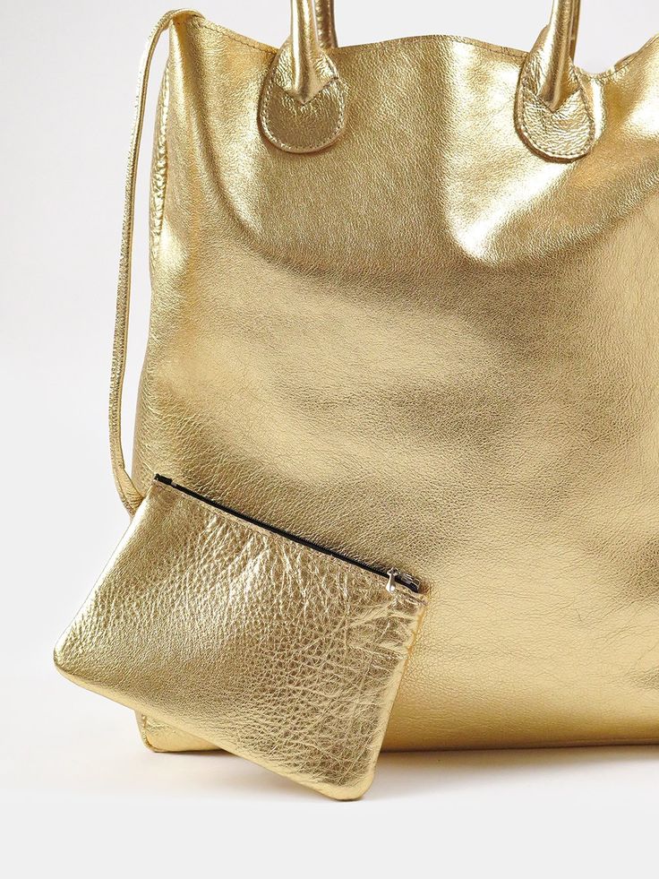 simple shopping tote in metallic leather with tethered inner pouch. bag interior is raw. measures 16" x 14" x 6" with 17" strap. pouch measures 6.5" x 4.5". made in california. erica tanov Erica Tanov, Gold Tote Bag, Bison Leather, Shopping Totes, Bag Interior, Vanity Bag, Barrel Bag, Daily Essentials, Shopping Tote