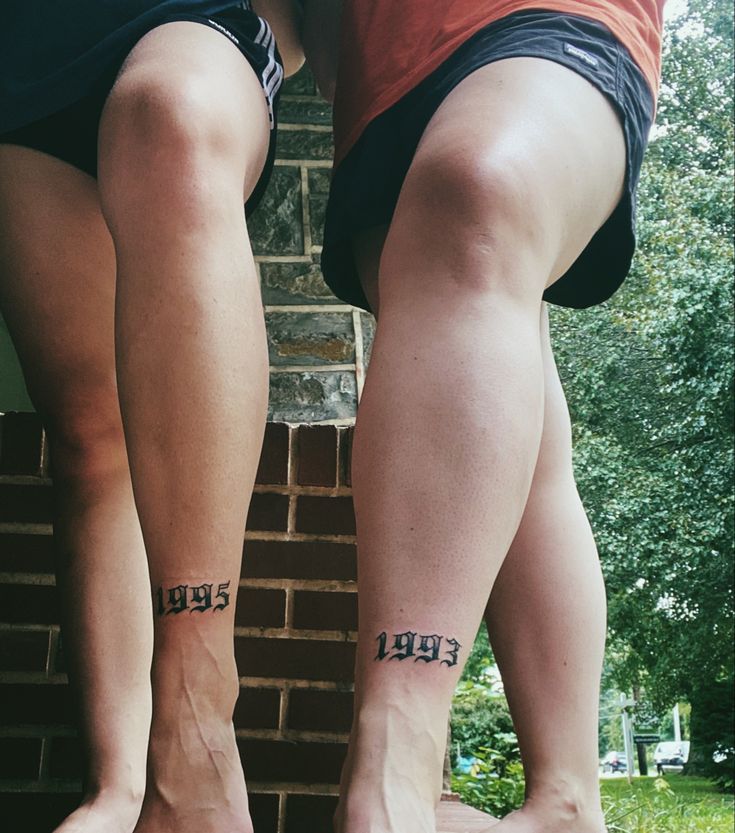 two people standing next to each other with tattoos on their legs