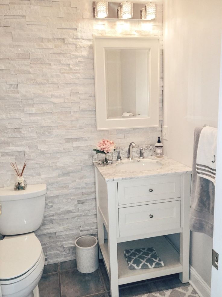 a white toilet sitting next to a sink in a bathroom under a vanity with a mirror above it