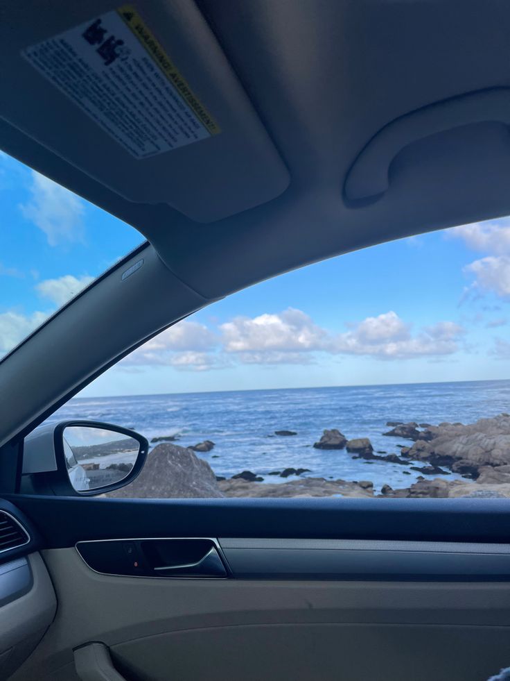 the view from inside a car looking out at the ocean and rocky coastline in the distance