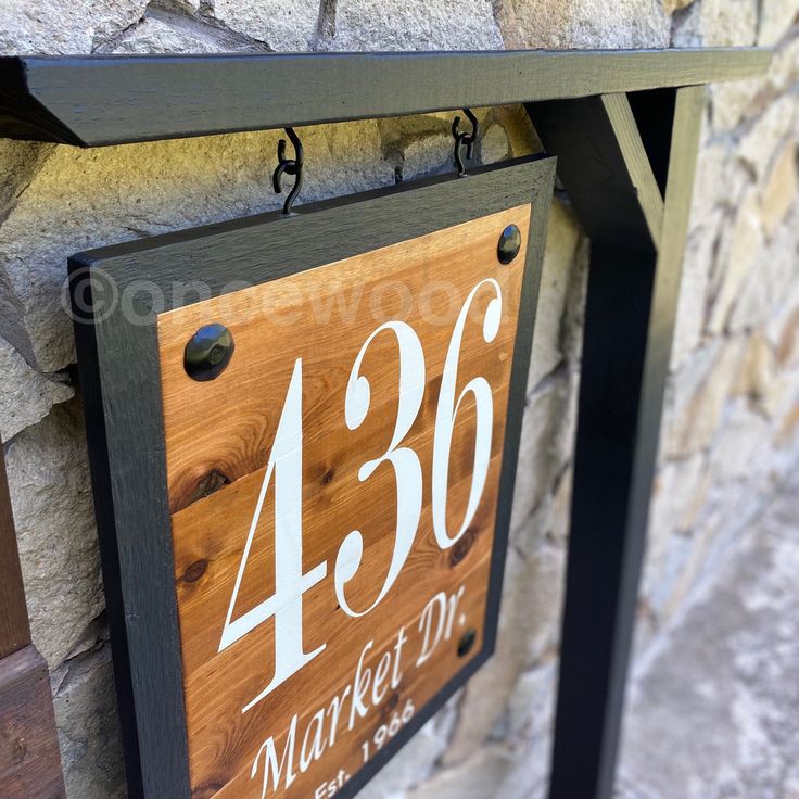 a wooden sign hanging from the side of a stone wall next to a brick building