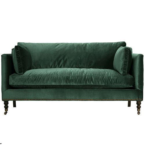 a green velvet couch with wooden legs