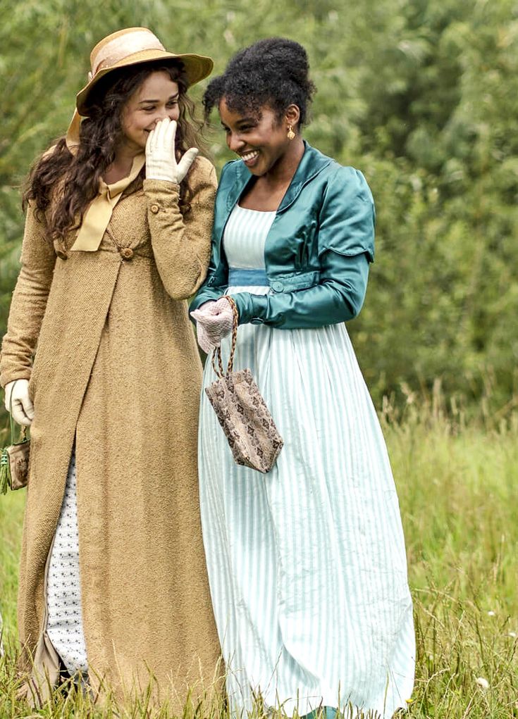 two women in dresses and hats are talking on the phone while walking through tall grass