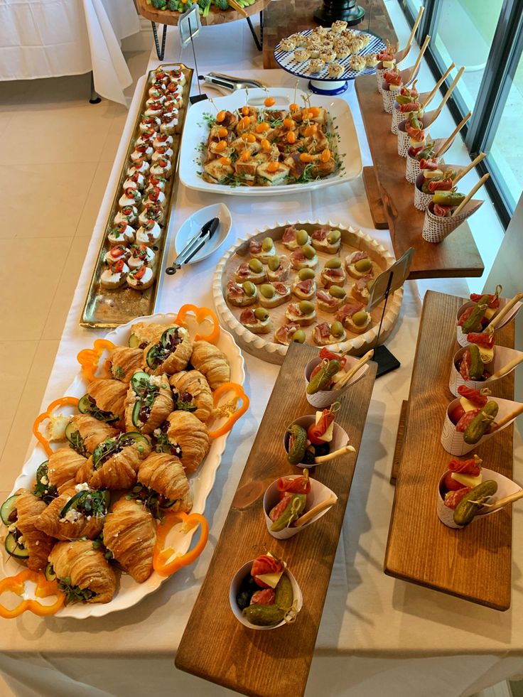 an assortment of appetizers and snacks displayed on wooden trays at a buffet table