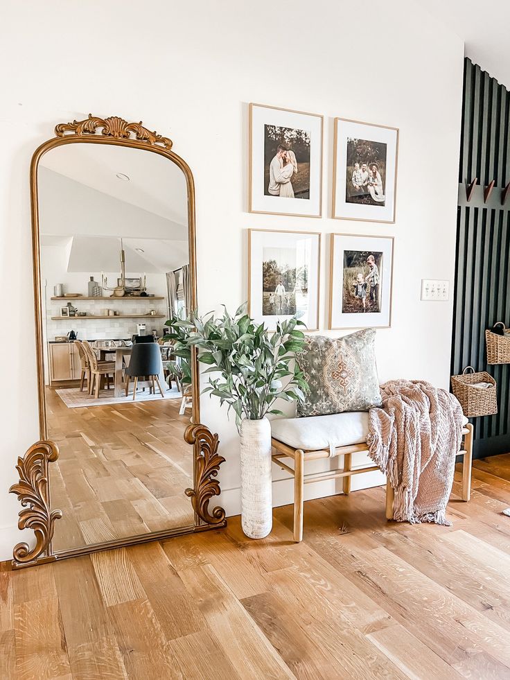 a mirror sitting on top of a wooden floor next to a couch and table with pillows