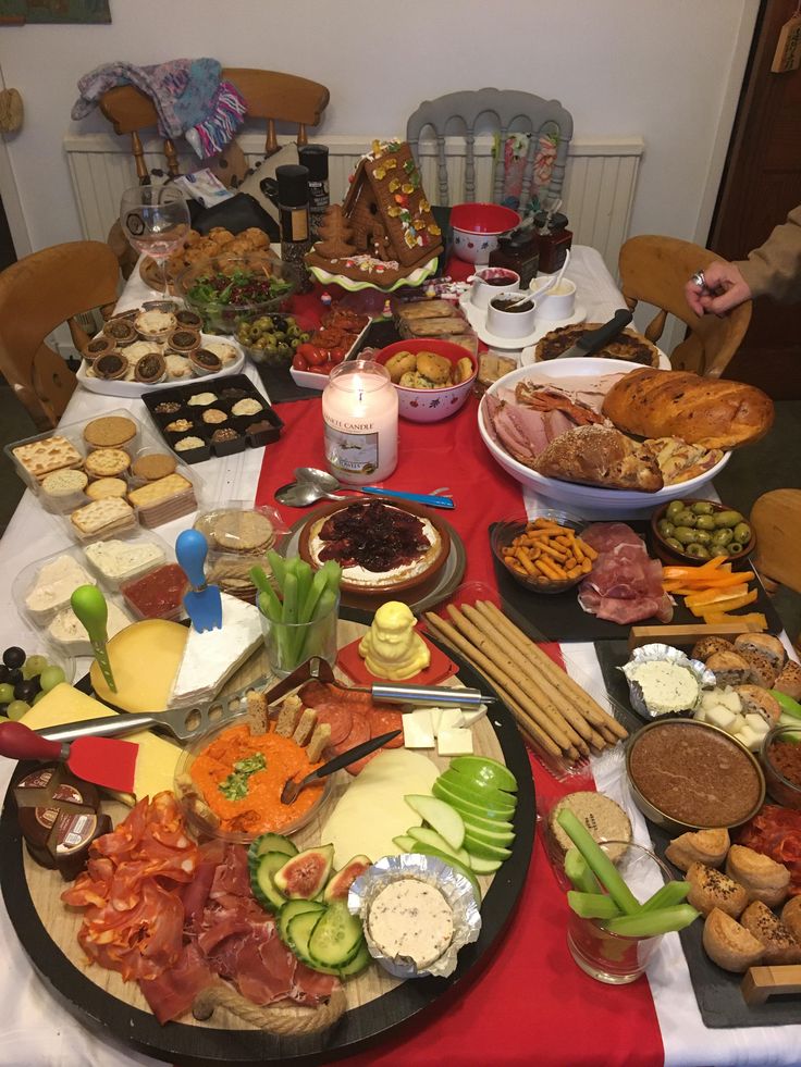 a table full of food with plates and bowls on it, including cheeses, crackers, meats, and vegetables