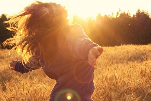 a woman in a field with the sun shining through her hair