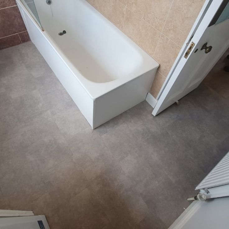 a bath tub sitting next to a white door in a bathroom with tile flooring