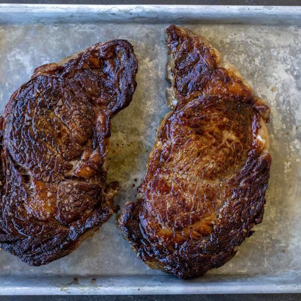 two steaks sitting on top of a metal pan