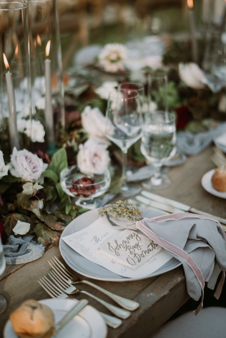 the table is set with white plates and silverware, napkins, and flowers